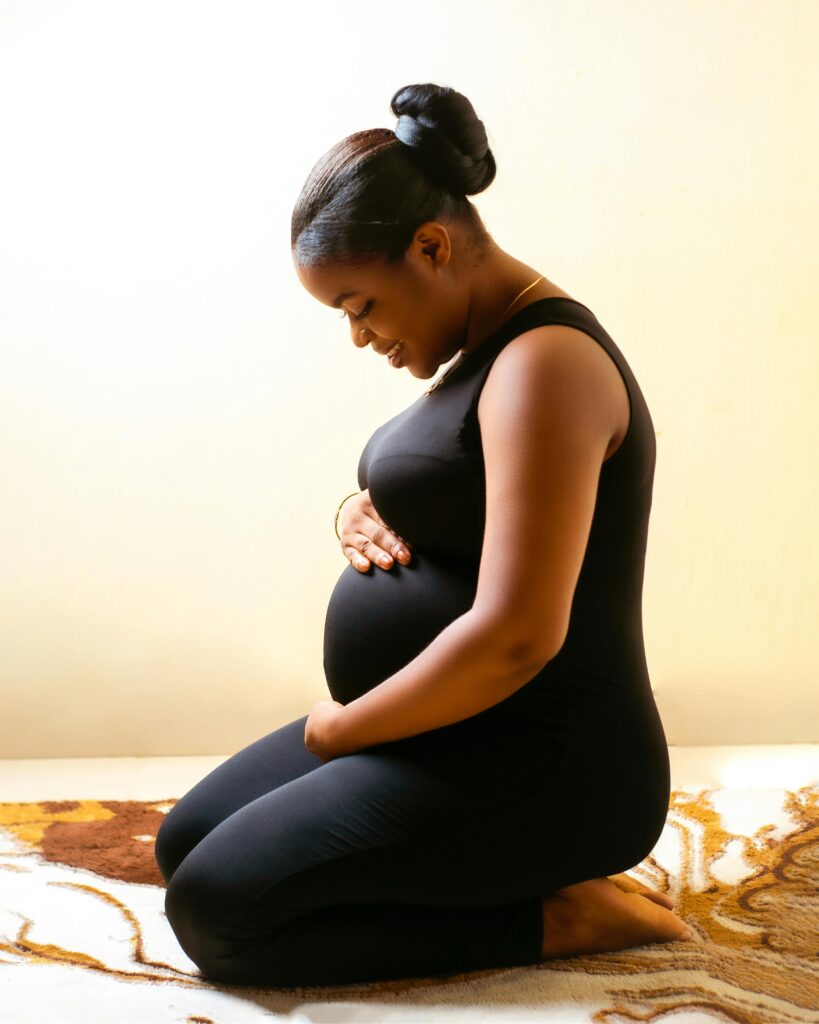 Pregnant woman sitting on her knees and holding her belly.