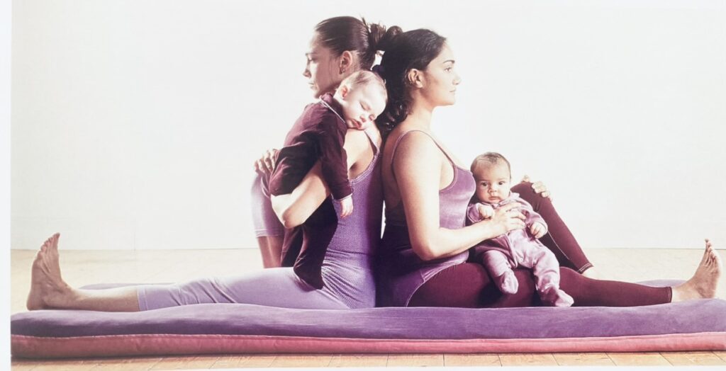 Two mothers holding their babies in correct yoga positions.